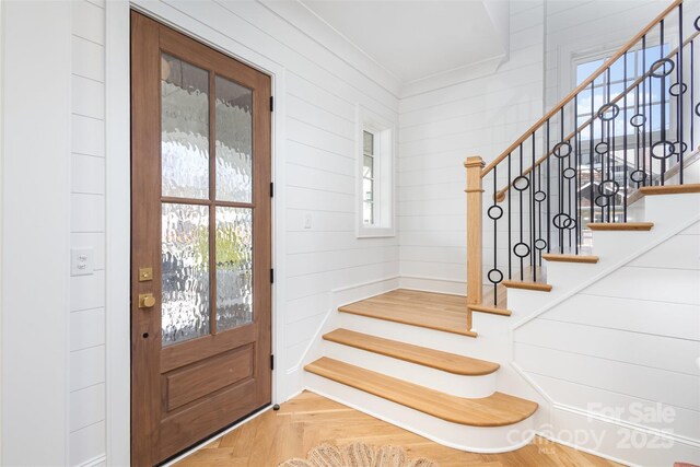 foyer entrance with stairs and crown molding
