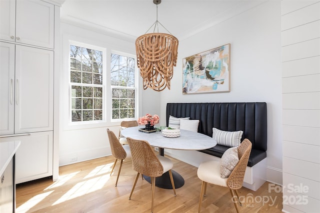 dining area with baseboards, breakfast area, light wood-type flooring, and ornamental molding