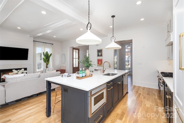 kitchen with crown molding, light wood-type flooring, a healthy amount of sunlight, a sink, and a breakfast bar area