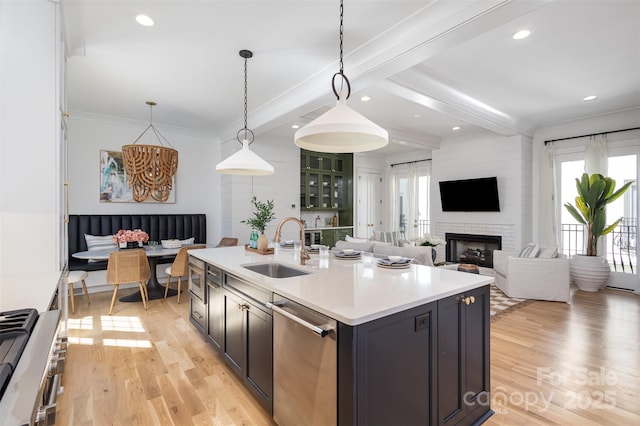 kitchen with a sink, light wood-style flooring, appliances with stainless steel finishes, and a healthy amount of sunlight