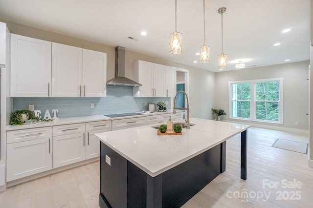 8225 Long Island Rd, Catawba, NC 28609 - kitchen featuring wall chimney exhaust hood, light wood-style floors, a kitchen island with sink, white cabinetry, and backsplash