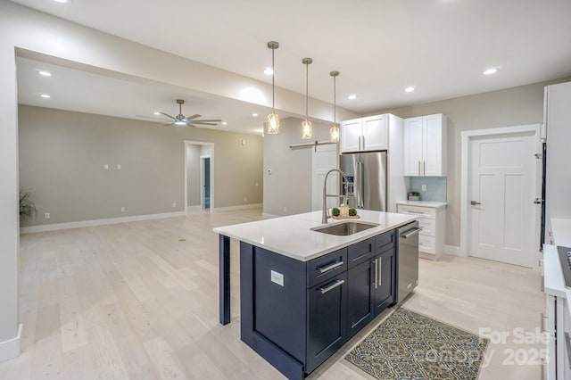 8225 Long Island Rd, Catawba, NC 28609 - kitchen with a barn door, a sink, stainless steel appliances, light wood-style floors, and white cabinets