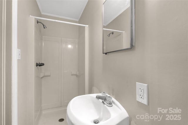 full bathroom with crown molding, walk in shower, and a sink