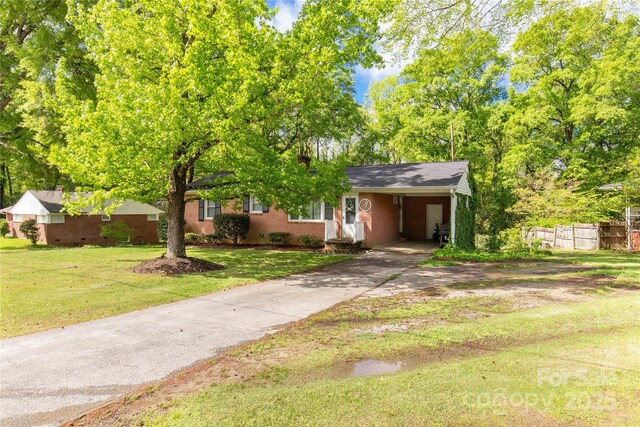 view of front facade featuring concrete driveway, a front lawn, an attached carport, brick siding, and fence