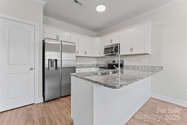 2032 Summey Ave, Charlotte, NC 28205 - kitchen featuring appliances with stainless steel finishes, a peninsula, white cabinets, light wood-type flooring, and ornamental molding