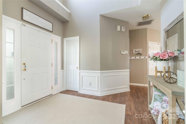 foyer entrance with wainscoting, wood finished floors, and visible vents