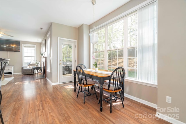 dining space featuring baseboards, a ceiling fan, wood finished floors, and visible vents
