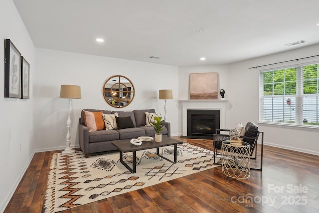 living room with baseboards, visible vents, and wood finished floors