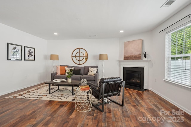 living area with a fireplace with flush hearth, dark wood-style flooring, visible vents, and recessed lighting