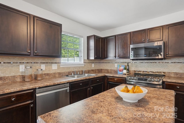 kitchen with dark brown cabinetry, stainless steel appliances, backsplash, and a sink