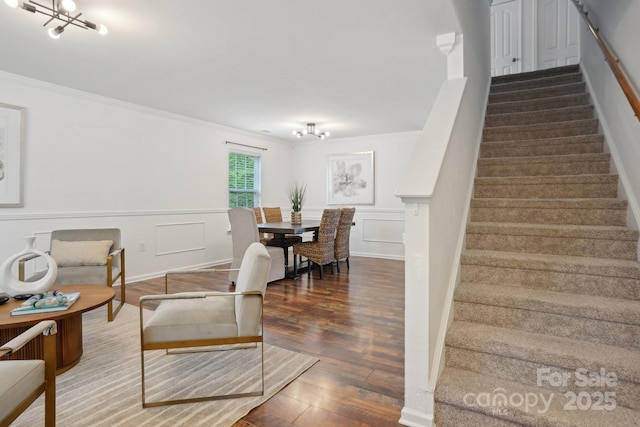 interior space featuring a chandelier, stairs, a decorative wall, ornamental molding, and wood finished floors