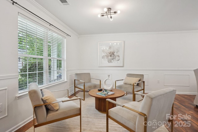 living area featuring wood finished floors, a healthy amount of sunlight, and crown molding