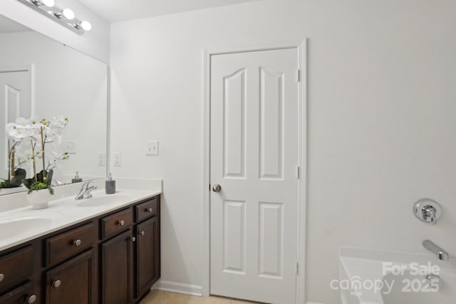 full bath featuring baseboards, double vanity, and a sink