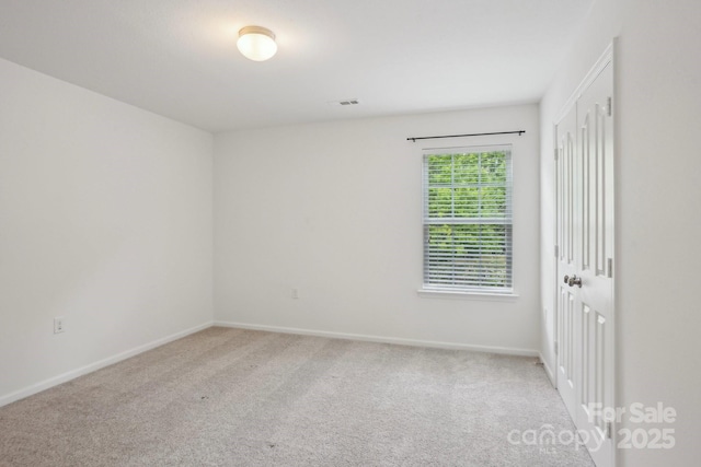 spare room featuring carpet, visible vents, and baseboards