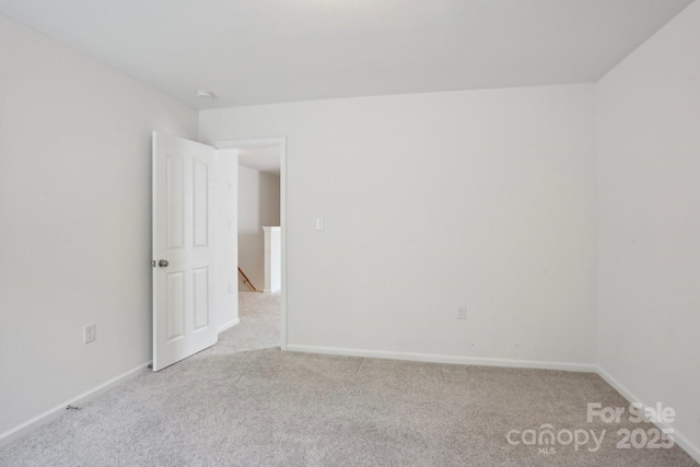spare room with baseboards and light carpet