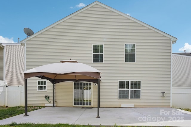 back of property with fence, a gazebo, and a patio area