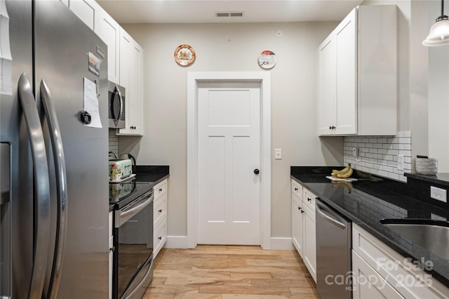 124 Foxden Dr Unit 303, Fletcher, NC 28732 - kitchen with appliances with stainless steel finishes, light wood-style floors, white cabinetry, dark stone countertops, and backsplash