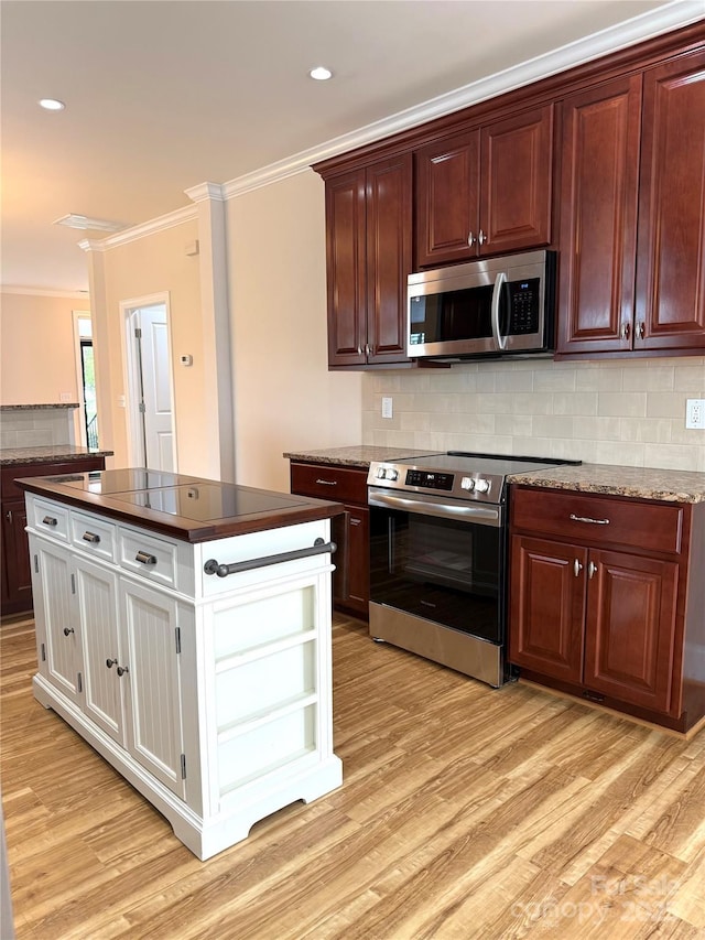 216 Harrison Ln Unit 4, Locust, NC 28097 - kitchen featuring crown molding, appliances with stainless steel finishes, light wood-style floors, a kitchen island, and backsplash