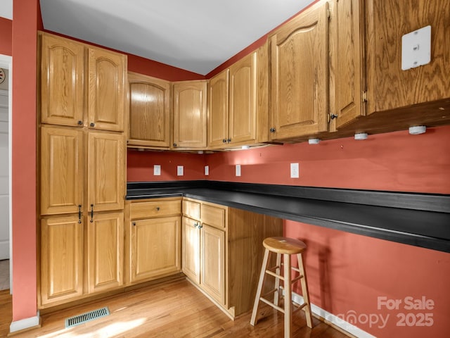 940 Hugh Champion Rd, Tryon, NC 28782 - kitchen with light wood-type flooring, dark countertops, visible vents, and a breakfast bar area