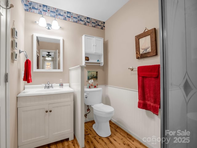 940 Hugh Champion Rd, Tryon, NC 28782 - bathroom with toilet, a ceiling fan, vanity, wood finished floors, and a wainscoted wall