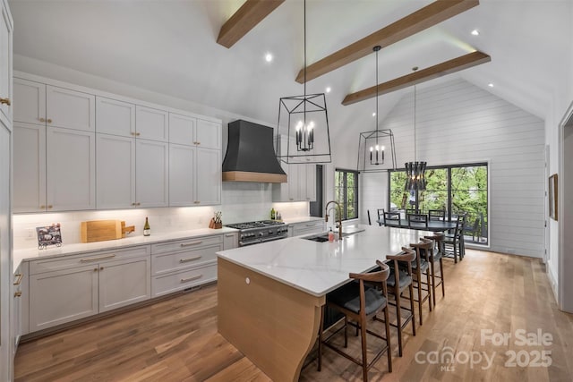 438 Wonderwood Dr, Charlotte, NC 28211 - kitchen featuring custom exhaust hood, light wood-type flooring, beamed ceiling, decorative backsplash, and range with two ovens