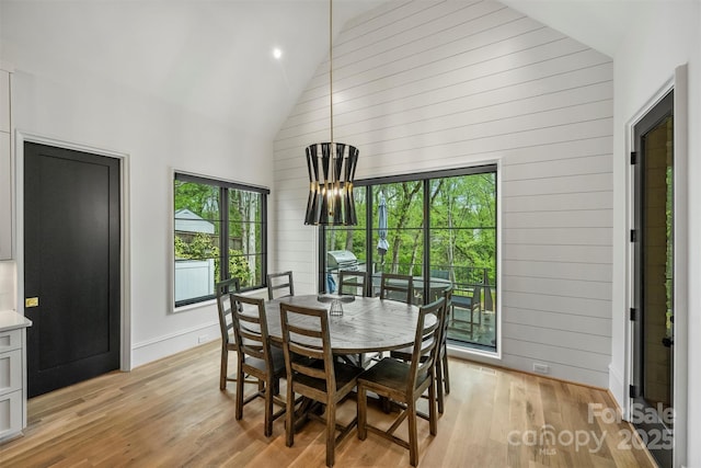 438 Wonderwood Dr, Charlotte, NC 28211 - dining space featuring wooden walls, high vaulted ceiling, an inviting chandelier, and light wood-style floors
