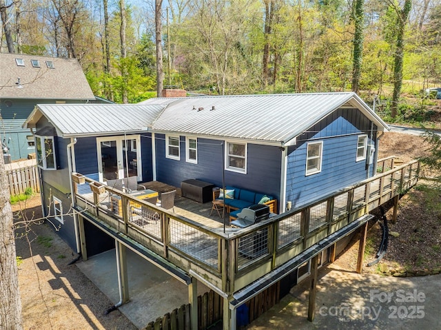 rear view of property featuring a wooden deck, fence, and metal roof