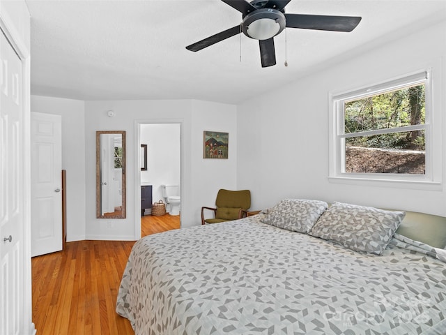 bedroom featuring ensuite bath, light wood-style floors, and a ceiling fan