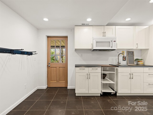 kitchen featuring white microwave, visible vents, and white cabinets