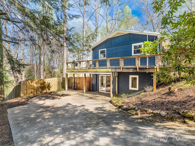 view of front facade with board and batten siding, fence, a deck, and driveway