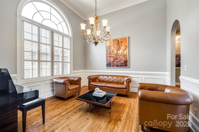 1126 Blowing Rock Cv, Fort Mill, SC 29708 - living room with arched walkways, a chandelier, crown molding, light wood finished floors, and wainscoting