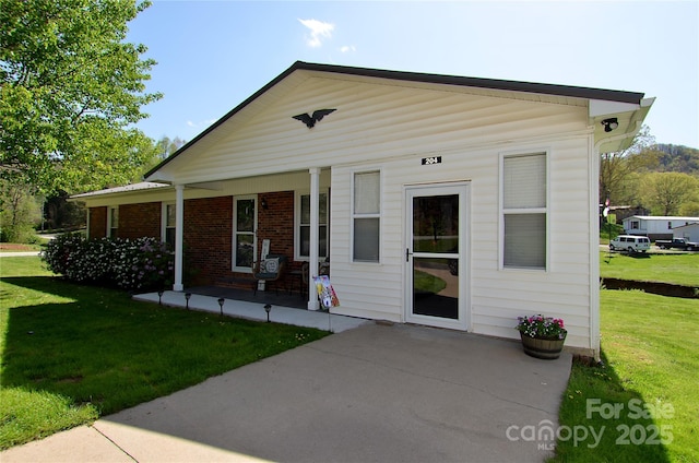 view of front of home featuring brick siding, a front lawn, and covered porch