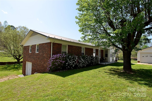 view of home's exterior with a yard, a garage, metal roof, and brick siding