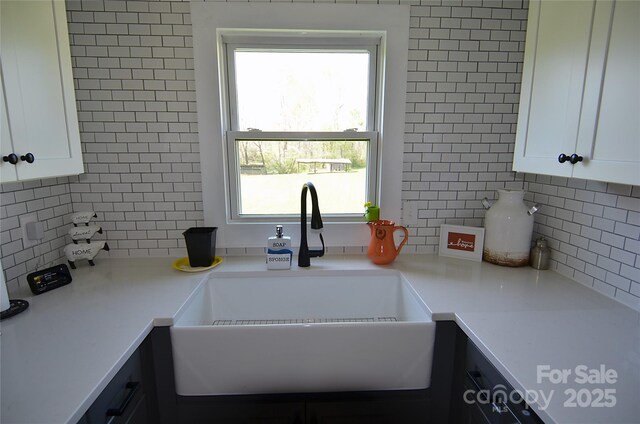 kitchen with white cabinets, tasteful backsplash, light countertops, and a sink