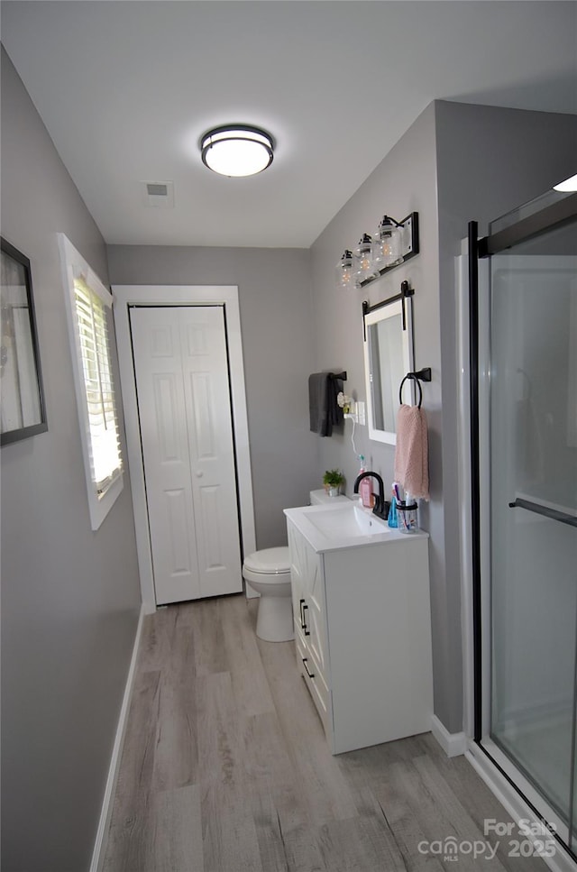 bathroom with vanity, visible vents, toilet, wood finished floors, and a stall shower
