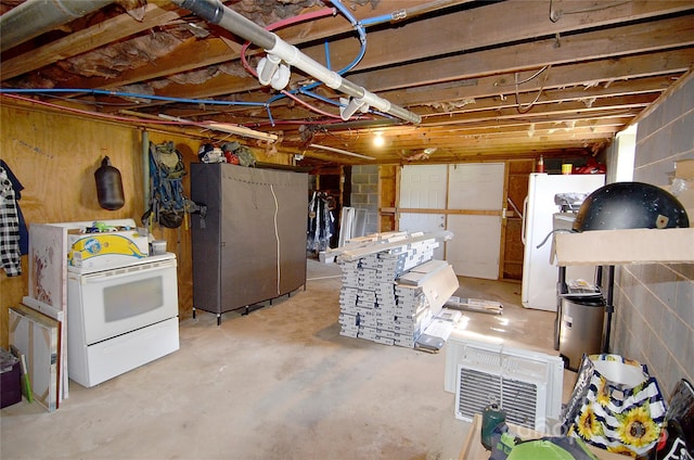 unfinished basement with freestanding refrigerator and concrete block wall