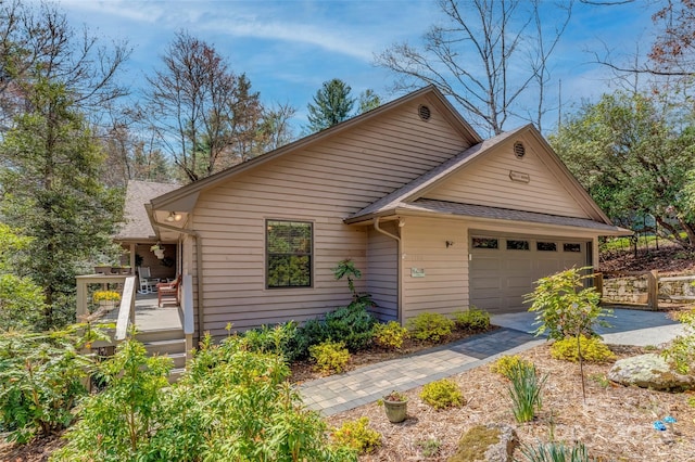 view of front of house featuring roof with shingles, a deck, driveway, and a garage