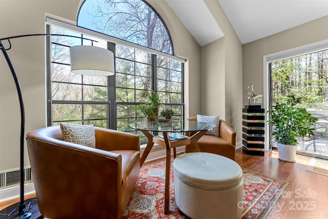living area featuring vaulted ceiling, wood finished floors, and baseboards