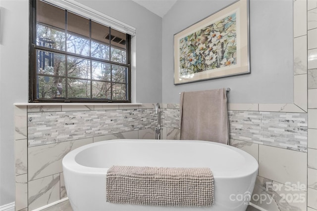 bathroom with tile walls and a freestanding tub