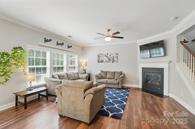 living room featuring dark wood-style flooring, visible vents, a ceiling fan, and ornamental molding