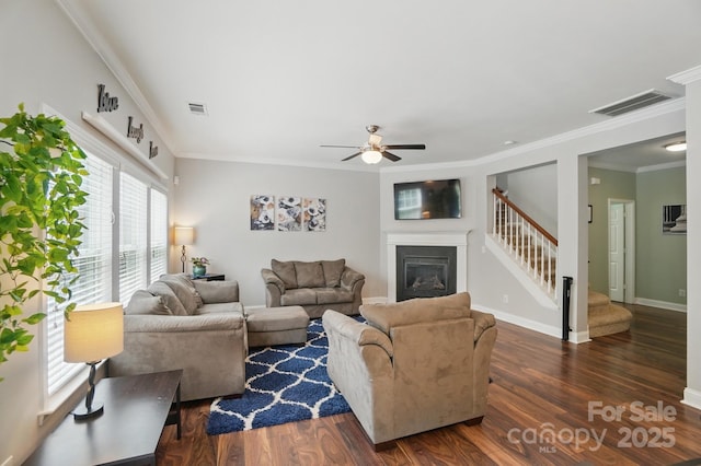 living room with wood finished floors, visible vents, stairs, and ornamental molding