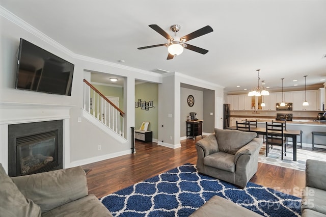 living area featuring recessed lighting, wood finished floors, baseboards, stairs, and ceiling fan with notable chandelier