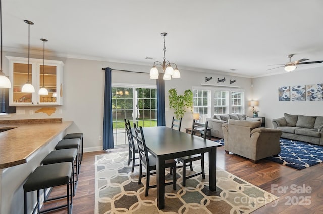 dining room featuring ceiling fan with notable chandelier, ornamental molding, wood finished floors, and plenty of natural light