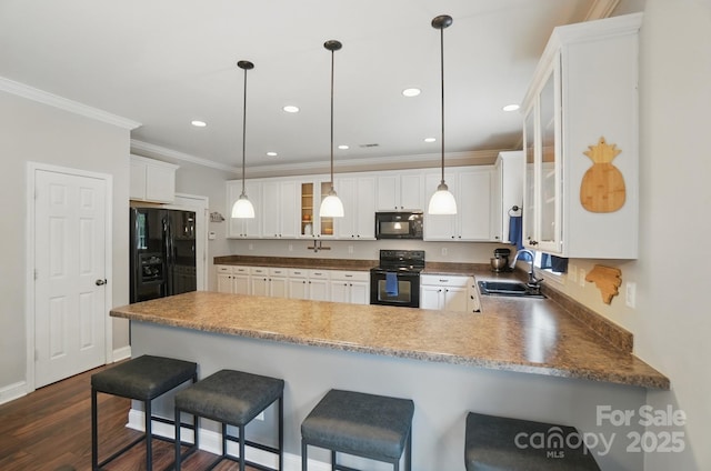 kitchen featuring a sink, crown molding, black appliances, a peninsula, and glass insert cabinets