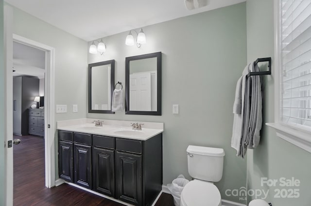 bathroom with wood finished floors, a sink, double vanity, and toilet