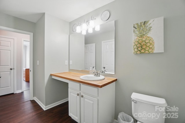 bathroom with wood finished floors, vanity, toilet, and baseboards