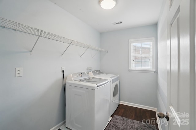 clothes washing area featuring washer and clothes dryer, laundry area, visible vents, baseboards, and dark wood-style floors