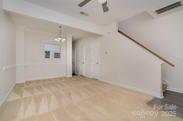 unfurnished living room with visible vents, ceiling fan with notable chandelier, carpet, and stairs
