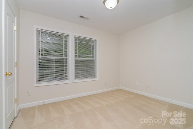 empty room featuring visible vents, baseboards, and light carpet