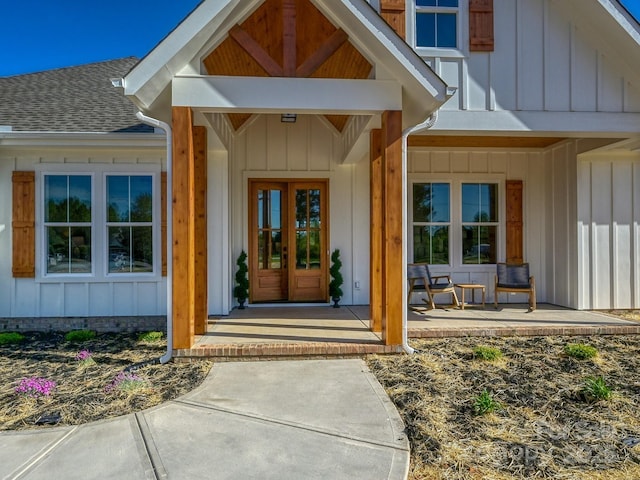 property entrance with board and batten siding, covered porch, and roof with shingles